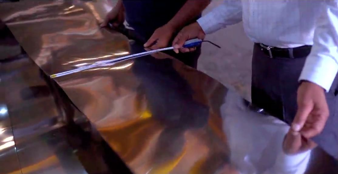 Hands checking a length of stainless strip before cutting