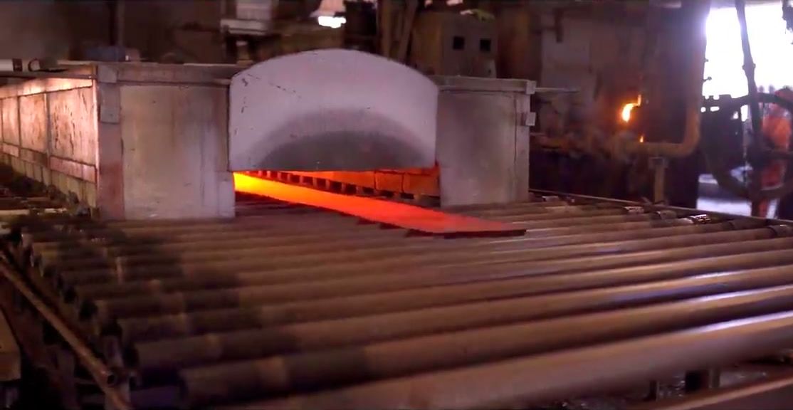 Red-hot steel leaving the reheating furnace onto the roller table